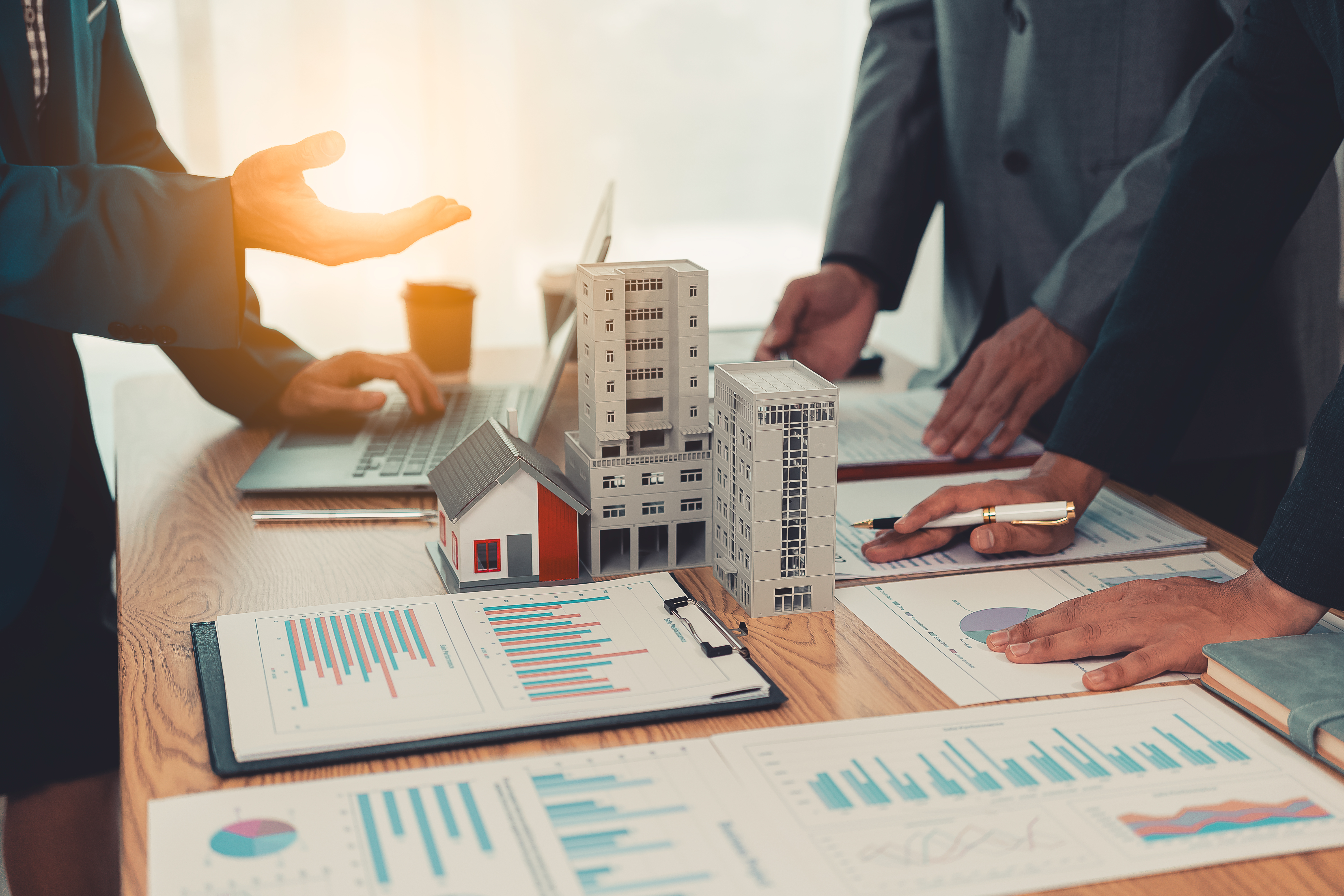 Real estate entrepreneurs meeting to sell a house, discussing real estate deals, with house plans on the table, symbolizing real estate investment and negotiations.