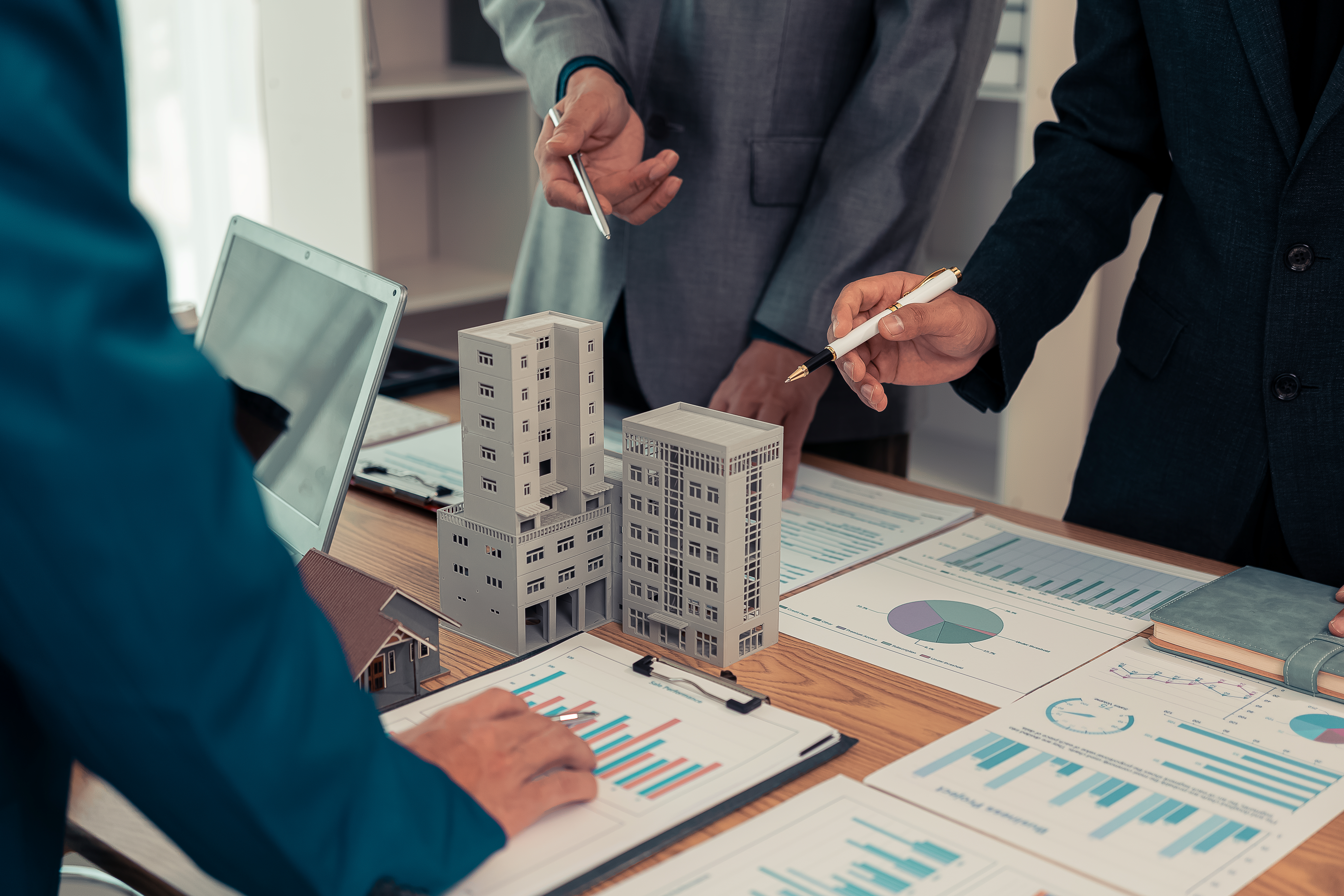 Real estate entrepreneurs meeting to sell a house, discussing real estate deals, with house plans on the table, symbolizing real estate investment and negotiations.